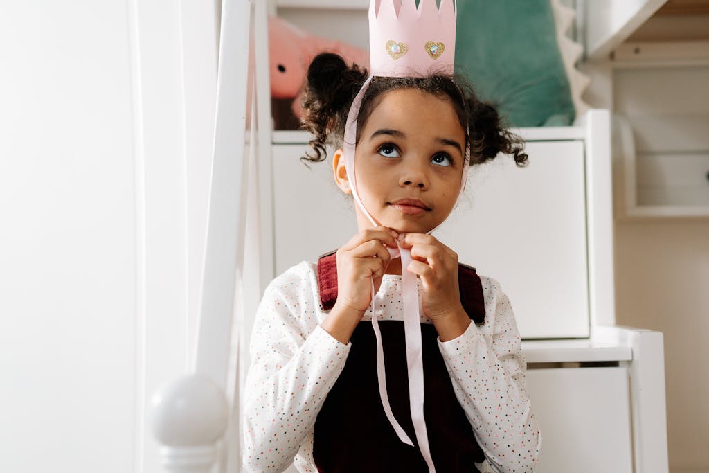 Adorable child wearing a handmade princess crown, enjoying dress-up indoors.